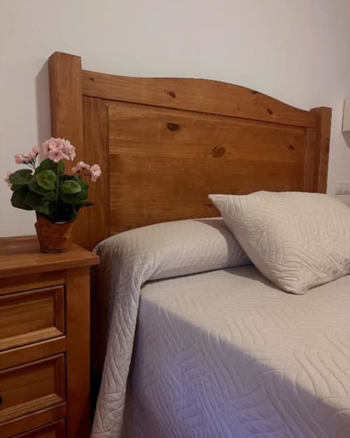 Detalle de cama doble con mobiliario rústico y decoración sencilla en Hostal Monterde de Albarracín