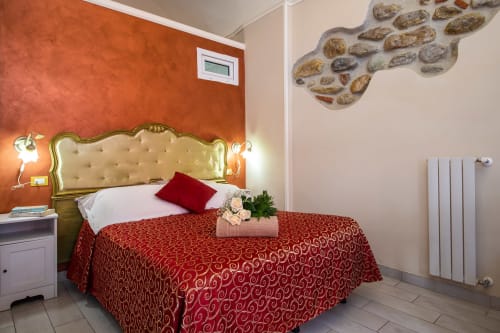 Angetto room at Casa Scola Loano B&B in Loano featuring a luxurious gold-trimmed bed with red bedspread and orange accent