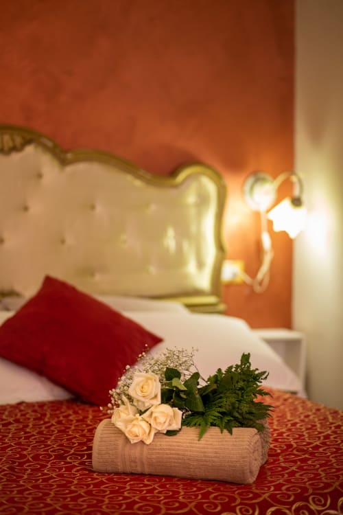Casa Scola Loano Angetto room with peach roses in wooden vase on red patterned carpet