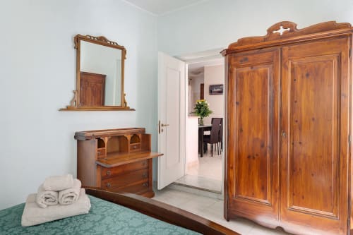 Camera da letto Annamaria di Casa Scola Loano con armadio in legno, scrivania, specchio e biancheria verde