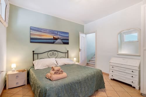 Camera da letto Annamaria di Casa Scola Loano B&B con parete accent verde, struttura letto in metallo, arredi bianchi e atmosfera costiera