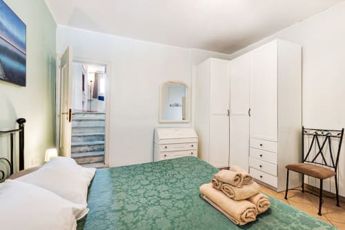 Camera Annamaria di Casa Scola Loano con letti gemelli, armadio bianco e coperta turchese