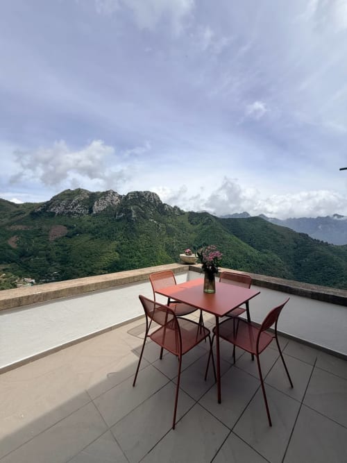 Red table and chairs on mountain view terrace at Adagio Ravello, Ravello, Italy