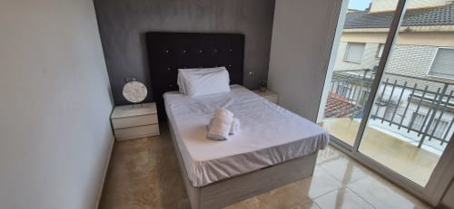 Dormitorio moderno en Apt. Dàlies de Estada Rural con cama queen, cabecero negro, balcón con vistas a la ciudad