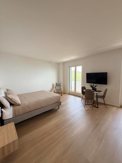 Modern studio bedroom at Adagio Ravello with sea view, featuring sofa bed, dining area, flat-screen TV, and terrace access.
