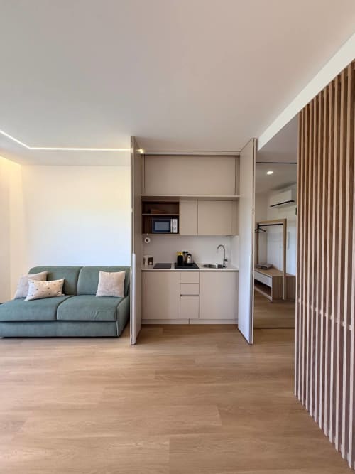 Modern studio at Adagio Ravello with gray sofa, open kitchen with white cabinetry, and wood flooring