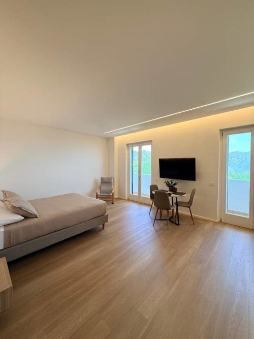 Modern studio room at Adagio Ravello with sea view, bed, TV, dining area, and terrace overlooking Ravello coast