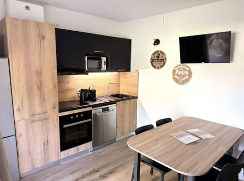 Modern kitchen with dining table in ALMA ROSSA villa, Lecci, featuring black cabinetry and stainless steel appliances