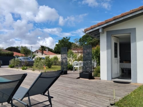 Wooden deck with lounge chairs, modern cottage with terrace, garden views, and pool area at La Pause Landaise, Magescq