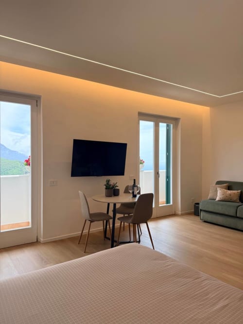 Modern villa suite at Adagio Ravello with sea view, dining area, flat-screen TV, and terrace access in Ravello, Italy