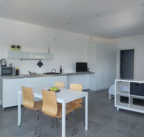 Modern open-plan kitchen and dining area at Adagio Ravello villa in Ravello with white cabinetry, natural wood chairs, and