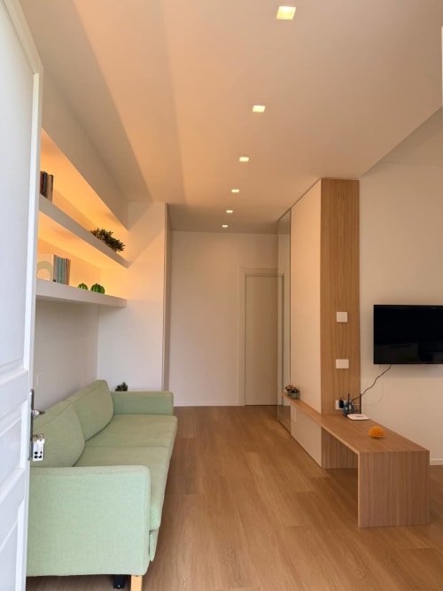 Modern cottage interior at Adagio Ravello with green sofa, wood furnishings, ambient lighting, and sea view access