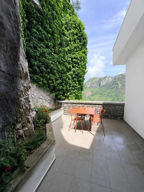 Terrace at Adagio Ravello villa in Ravello with orange furniture, ivy-covered walls, and mountain views