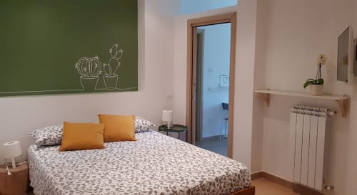 Adagio Ravello cottage bedroom with patterned bed, orange pillows, green chalkboard wall, and sea view in Ravello
