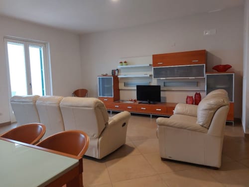 Spacious living room at Adagio Ravello cottage in Ravello with cream leather recliners, wood cabinetry, and sea views through