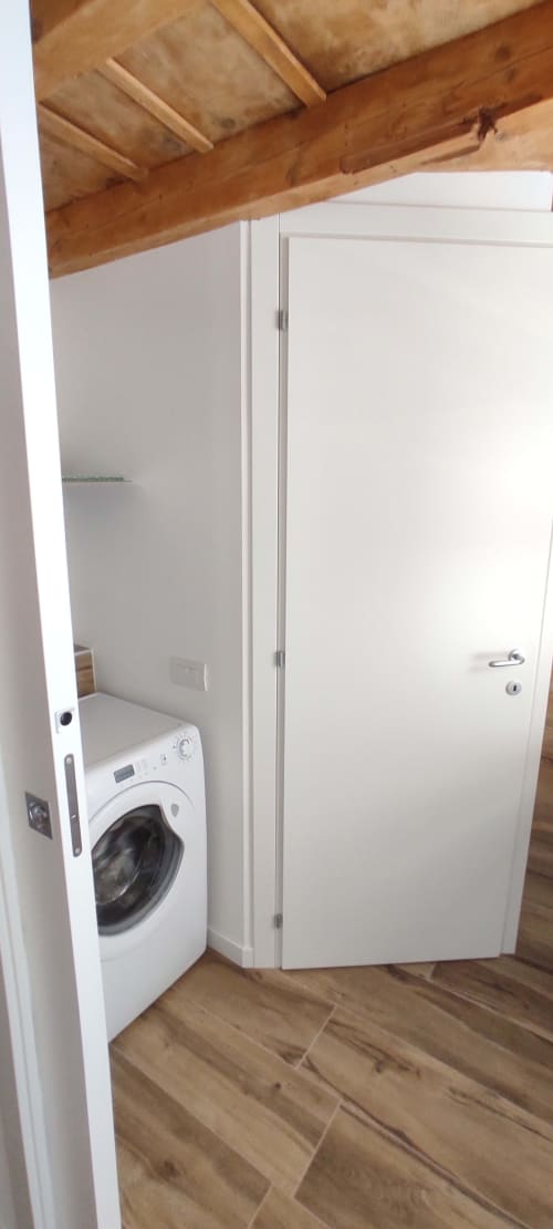Waschküche im B Loft Apartment im Bergamo City Center mit weißer Waschmaschine und weißem Lagerungstür