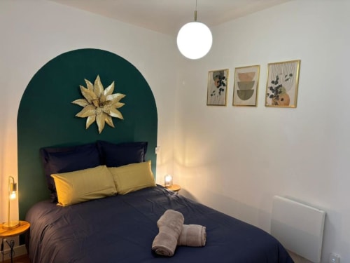 Chambre Midori aux Logis d'Emma avec literie bleu foncé, coussin doré, tête de lit arquée émeraude ornée d'une étoile dorée