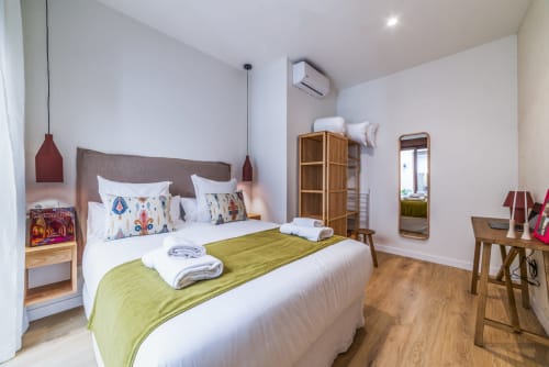 Dormitorio moderno en Los Patios de Feria de Sevilla con cama matrimonial, manta verde, muebles de madera y aire acondicionado