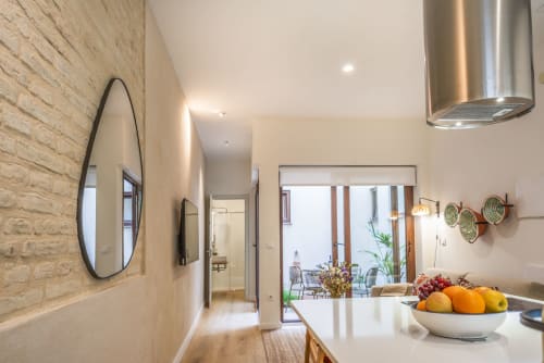 Cocina moderna en apartamento Los Patios de Feria, Sevilla, con encimeras blancas, campana acero inoxidable y frutero
