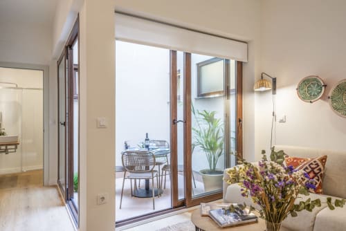 Moderno salón de apartamento con acceso a terraza en Los Patios de Feria de Sevilla, con sofá, flores y exterior