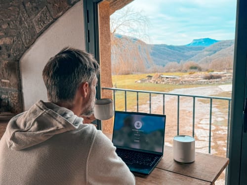 Guest working at laptop with mountain views from La casa de la masia, Susqueda, Girona