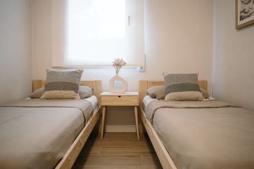 Twin bedroom with wooden beds and neutral décor at Finques Garcia Enrich apartment in Palafrugell