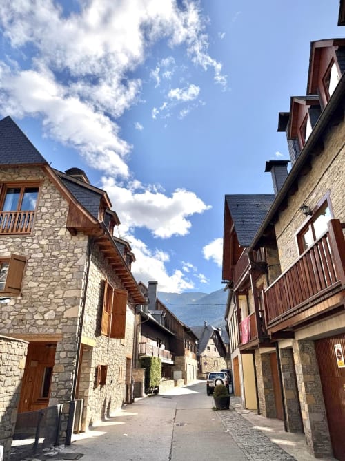 Calle de piedra en el pueblo de Vielha con edificios tradicionales de montaña, balcones y cielo despejado - Apartamento ERA CLAU HOMES