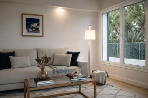 Modern living room in Palafrugell apartment with beige sofa, wooden table, floor lamp, and garden view through large windows