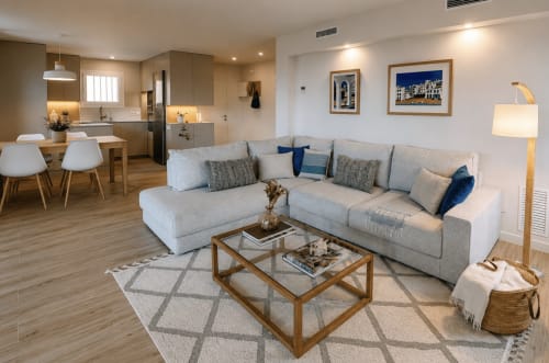 Modern apartment living room with gray sectional sofa, wooden coffee table, and open kitchen at Finques Garcia Enrich,