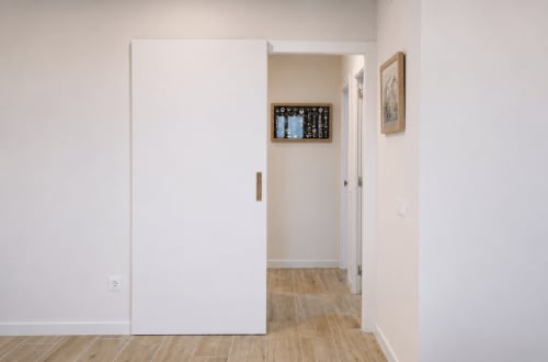 Modern hallway with white sliding closet door and wooden floors in Palafrugell apartment