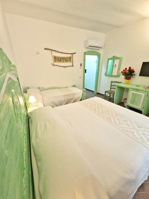 Camera luminosa a Regnos Altos Boutique Rooms a Bosa con letti gemelli, arredamento verde, aria condizionata e servizi moderni