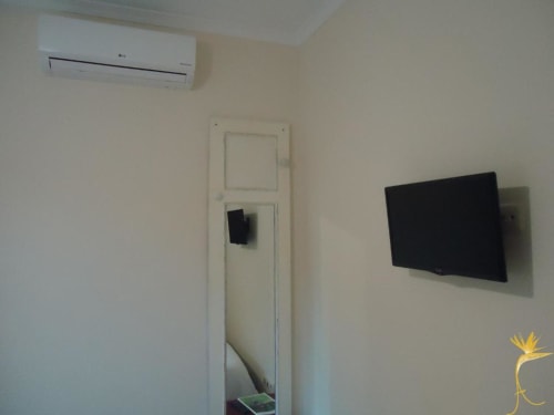 Quarto moderno em chalé com TV de tela plana, ar-condicionado e decoração minimalista na Casa Estrelícia-Dourada