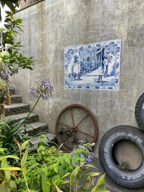 Pátio rústico da Casa Estrelícia-Dourada Garcês em São Vicente com parede desgastada e painel de azulejos azuis decorativos