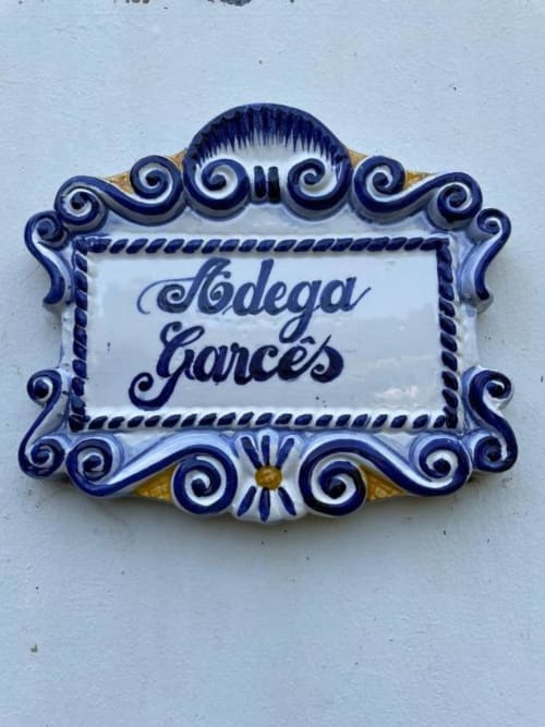 Placa decorativa de cerâmica azul e branca com inscrição 'Bodega Garcês' na Casa Estrelícia-Dourada Garcês em São Vicente, Portugal