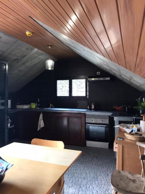 Cozinha moderna com armários pretos, teto de madeira e mesa de jantar na villa Casa Estrelícia-Dourada Garcês em São Vicente