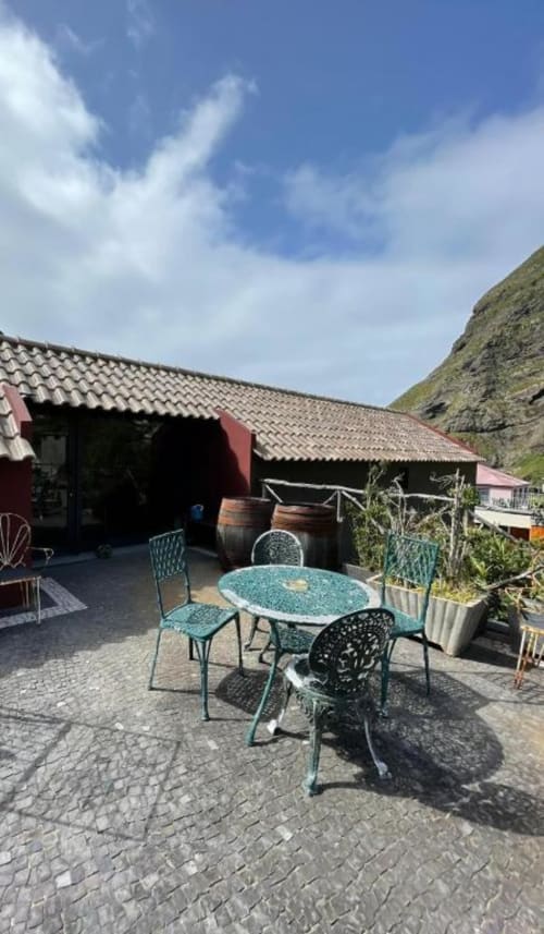 Pátio externo com mesa de jantar turquesa e cadeiras na vila A Casa Estrelícia-Dourada Garcês em São Vicente, Portugal,