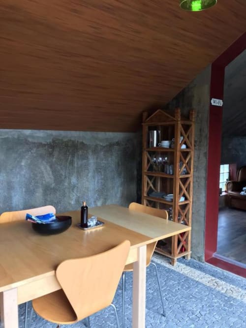 Área de refeições na villa Adega Garcês da Casa Estrelícia-Dourada Garcês, São Vicente com mesa de madeira, parede de concreto e