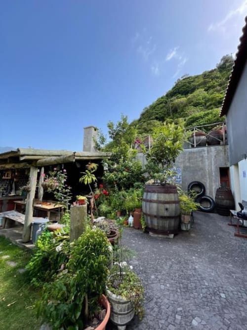Pátio rústico da Casa Estrelícia-Dourada Garcês com jardim, barril de madeira e vistas para a montanha