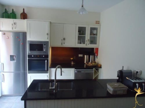 Cozinha moderna na cottage Casa Mãe em A Casa Estrelícia-Dourada Garcês, São Vicente com bancada preta e armários brancos,