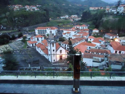 Vista ao entardecer da casarão Casa Estrelícia em São Vicente com edifícios brancos, telhados de terracota e colinas florestadas