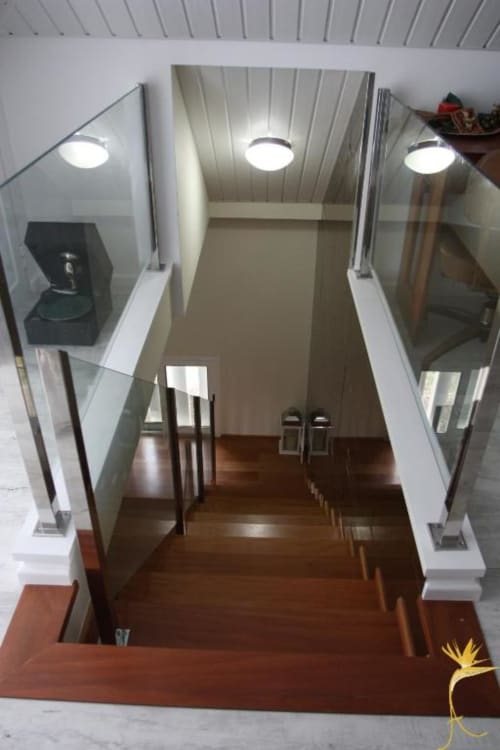 Corredor moderno da Casa Mãe com vidro temperado, piso de madeira e iluminação embutida no teto