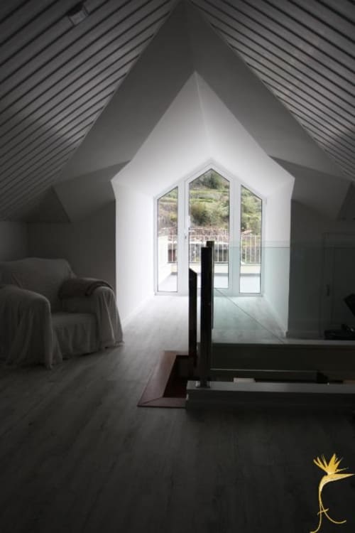 Quarto minimalista em loft com teto catedral, amplas janelas com vista para o oceano e montanhas de São Vicente, assoalho em madeira