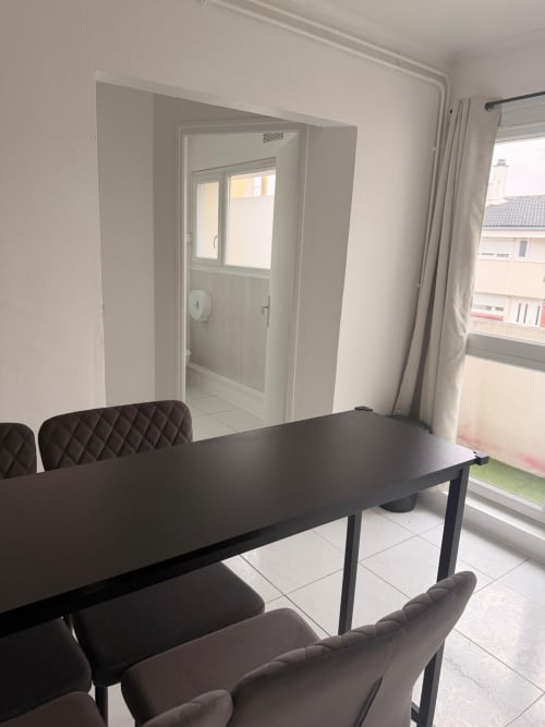 Salle à manger moderne dans un appartement 2 chambres à Kawichimmo Locations, Louvres, avec table noire, chaises matelassées et balcon