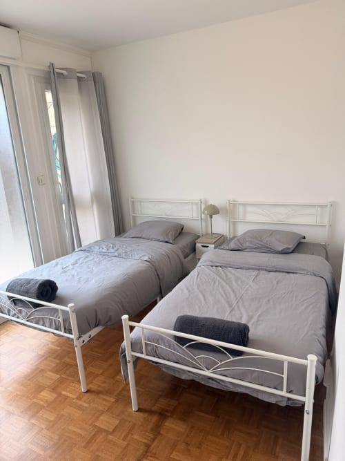 Chambre twin dans un appartement 2 chambres à l'hôtel Kawichimmo Locations à Louvres, France avec lits métalliques blancs