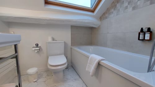 Salle de bain moderne de l'Hôtel Dandy à Rouen avec baignoire, toilettes, puits de lumière et sèche-serviettes électrique