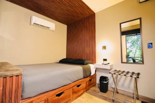 Habitación moderna del Contenedores Boutique Hotel con cama de estructura de madera, aire acondicionado, escritorio y vista al jardín desde la ventana