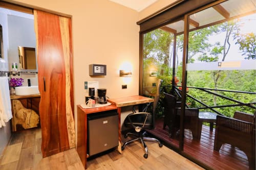 Moderno cuarto de hotel con escritorio de madera, balcón con vista al jardín y terraza en Contenedores Boutique Hotel, Costa Rica