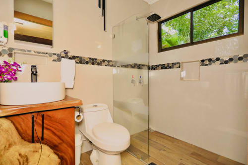 Baño moderno con lavamano redondo blanco, inodoro y ducha tipo walk-in en Contenedores Boutique Hotel, Costa Rica