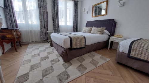 Chambre spacieuse à l'Hôtel Dandy à Rouen avec deux lits, têtes de lit violettes, tapis à motifs et grandes fenêtres grises