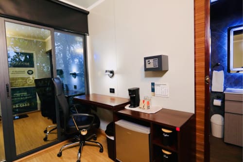 Espacio de trabajo moderno en la oficina del Contenedores Boutique Hotel con escritorio, silla, caja fuerte y estación de café en Costa Rica